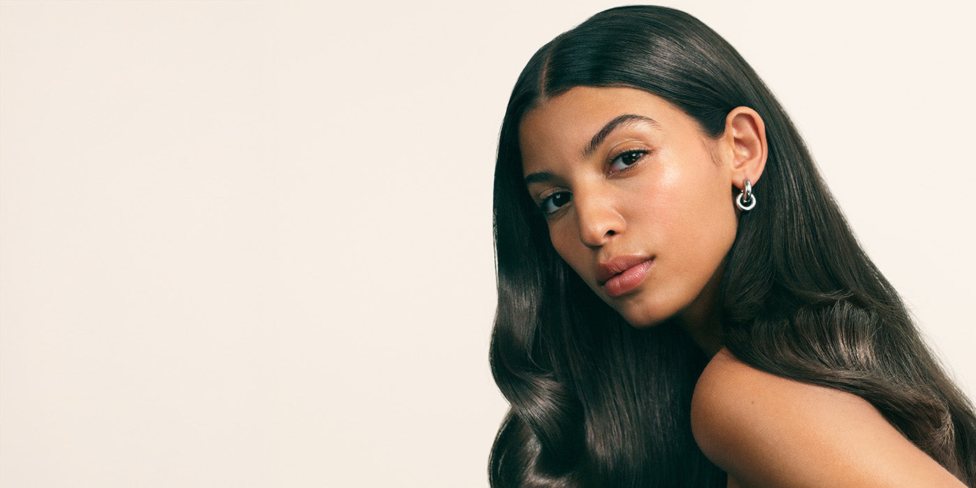 Woman with long dark glossy hair against beige background